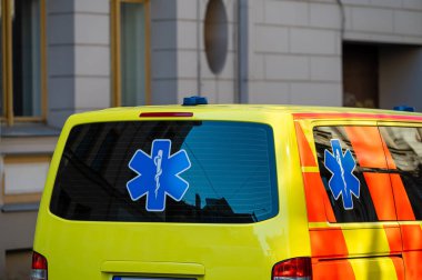 Kalabalık bir caddenin kenarına park edilmiş sarı bir ambulans acil durum arabası, yakın plan, seçici odaklı.