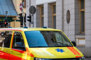 Kalabalık bir caddenin kenarına park edilmiş sarı bir ambulans acil durum arabası, yakın plan, seçici odaklı.