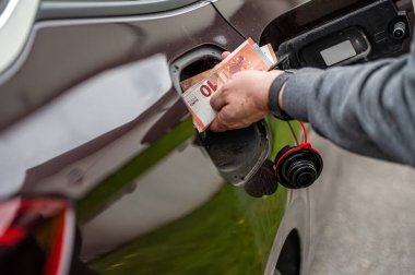 Arabanın deposuna para koyan adamın eli, yakın plan, pahalı yakıt konsepti, yakıt krizi