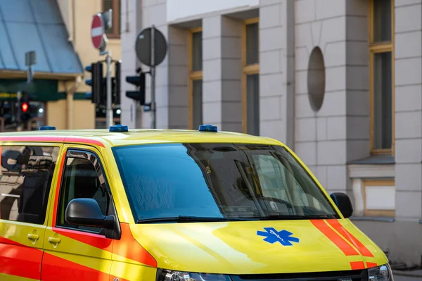 Kalabalık bir caddenin kenarına park edilmiş sarı bir ambulans acil durum arabası, yakın plan, seçici odaklı.