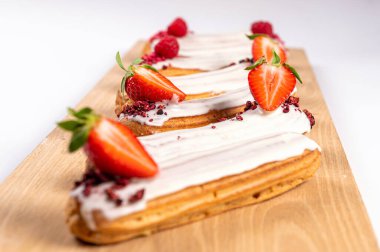 Ahşap bir tahtanın üzerinde jöleli ve çilekli ekler, beyaz, yakın plan.