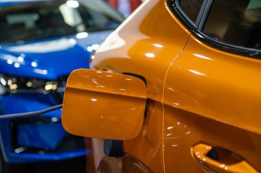 Şarj kablosunun fişi bir elektrikli arabaya takılı, istasyonda bir elektrikli arabayı şarj ediyor.