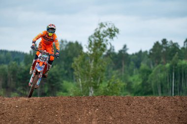 Dobele, Letonya, 18 Haziran 2022: Motokros yarışçısı havada zıplar ve gökyüzüne karşı sıçrama tahtasıyla havalanır.