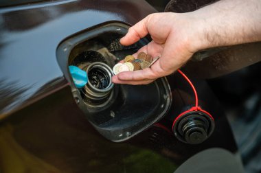 Otomobil deposuna bozuk para koyan adamın eli, yakın plan, pahalı yakıt konsepti, yakıt krizi
