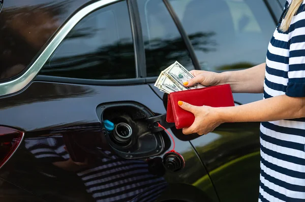 a woman s hand counts money while standing at an open fuel tank, the concept of rising fuel prices