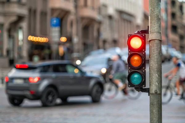 city crossing with a semaphore on blurred background with cars in the evening streets, red light