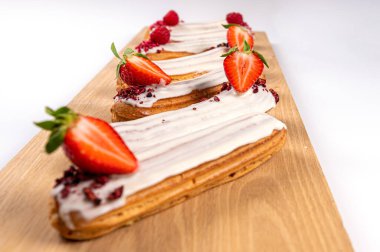 Ahşap bir tahtanın üzerinde jöleli ve çilekli ekler, beyaz, yakın plan.