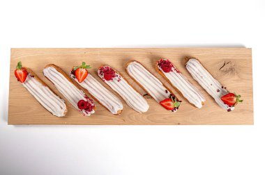 Ahşap bir tahtanın üzerinde jöleli ve çilekli ekler, beyaz tenha, yakın plan, üst manzara