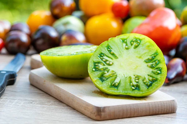 table with a cutting board with sliced tomatoes and different colored tomatoes in the background