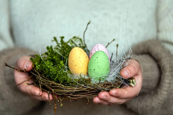 女性の手でカラフルなイースターの卵と巣 素朴なスタイルでイースターの装飾 — ストック写真