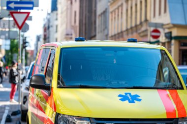 Kalabalık bir caddenin kenarına park edilmiş sarı bir ambulans acil durum arabası, yakın plan, seçici odaklı.