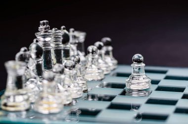 transparent glass chess on dark background, selective focus on pawn piece, close-up