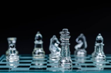 glass chess board game in black background ,selective focus on King, leadership ,winner concept