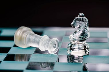 transparent glass chess on dark background, selective focus on knight piece, close-up