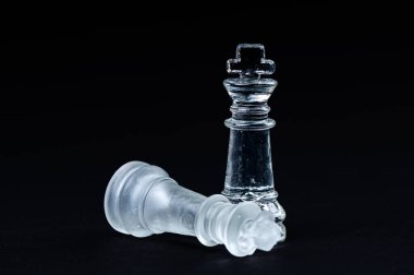 transparent glass chess on black background, selective focus on king piece, close-up