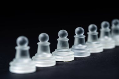 opaque glass chess pawn row on black background, selective focus, close-up