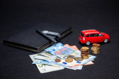 euro cash, notebook with pen and red toy car on black background, loan and insurance concept