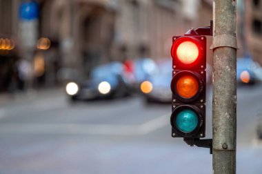 city crossing with a semaphore on blurred background with cars in the evening streets, red light