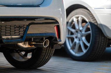 close-up of the wheels and bumpers of a car parked in the yard of a residential house, lower section