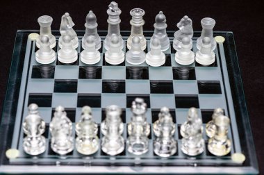 Set of transparent glass chess pieces over black, selective focus, copy space