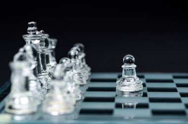 transparent glass chess on dark background, selective focus on pawn piece, close-up