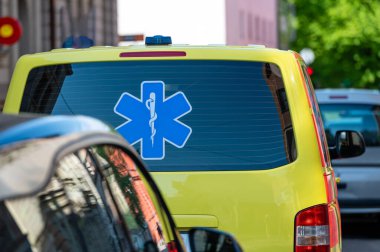 Kalabalık bir caddenin kenarına park edilmiş sarı bir ambulans acil durum arabası, yakın plan, seçici odaklı.