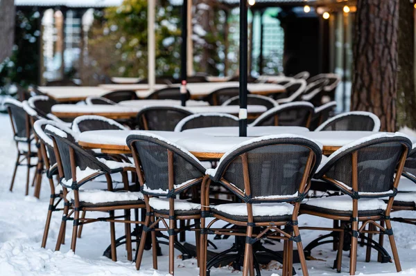Empty restaurant in winter, empty chairs and tables covered with snow