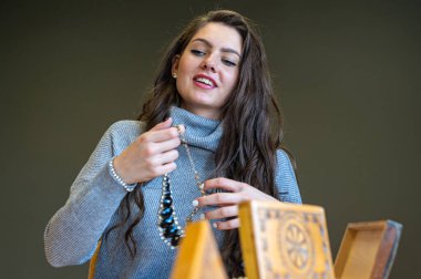 Aynada farklı takıları seçen ve deneyen bir kadının yansıması, yumuşak odak, yakın plan