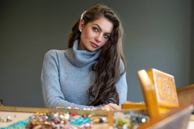 Aynada farklı takıları seçen ve deneyen bir kadının yansıması, yumuşak odak, yakın plan