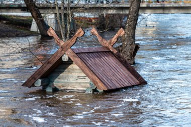 Bahar sellerinde taşan bir kuş evinin çatısına. Letonya, Dobele 'deki Berze Nehri' nde bir besleyici.