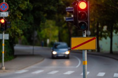 Sonbahar şehrinin odaksız arka planında kırmızı ışığı olan trafik semaforu, yakın plan