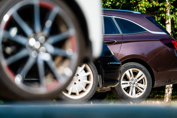 close-up of the wheels and bumpers of a car parked in the yard of a residential house, lower section