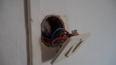 Kablolar kanıt odasında ve elektrik kutusundaki delikle duvardan sökülmüş üç delikli Avrupa soketi.