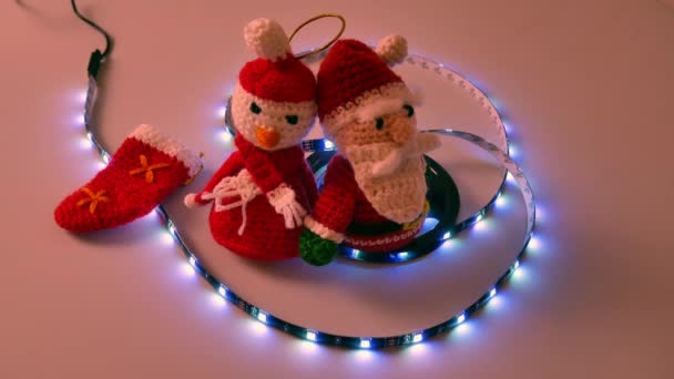 Crochê boneco de neve de Natal no fundo branco com usb levou luzes no pergaminho, piscando e vermelho estático, azul, verde, amarelo, sinônimo de Natal feliz e quente com crianças e entes queridos — Vídeo de Stock