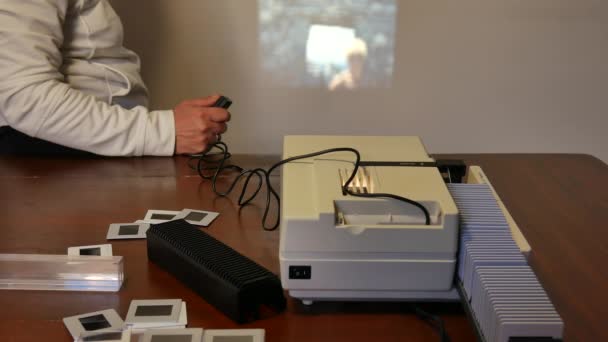 Антикварный белый слайд-проектор, видимый сбоку, сверху с разбросанными слайдами, свет проектора, проецируемого на белую стену, — стоковое видео