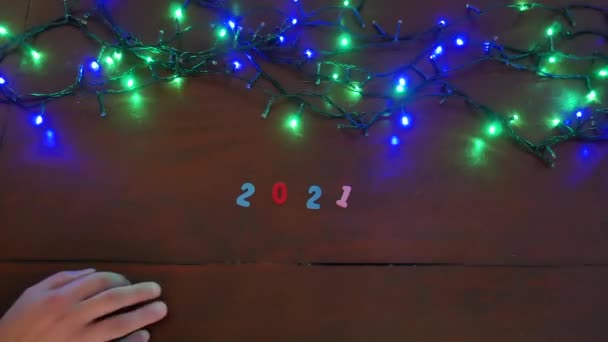 Transition vers la nouvelle année 2021 2022, avec des chiffres colorés et des lumières de Noël colorées clignotant par intermittence, une main jette 2021 et une autre main fait apparaître 2022. — Video