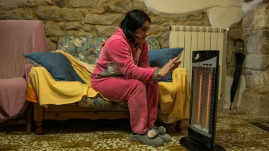 Evdeki kanepede pembe pijamalı hoş, serin bir kadın elektrikli ısıtıcının önünde ellerini ve ayaklarını ısıtıyor. Evimin sıcaklığında titriyordum..