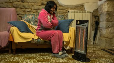 Evdeki kanepede pembe pijamalı hoş, serin bir kadın elektrikli ısıtıcının önünde ellerini ve ayaklarını ısıtıyor. Evimin sıcaklığında titriyordum..