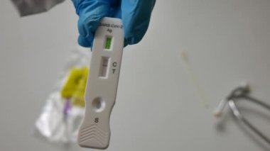 Antijenik çubuk, covid 19 virüs detektörü, test tüpü, sıvı, negatif sonuç, mavi eldivenli bir doktorun ellerinde.. 