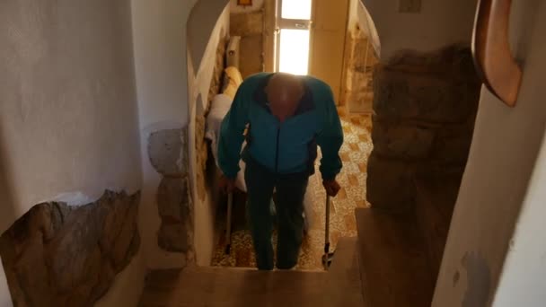 Idős férfi esik mankók a lépcsőn a házban, elveszti az egyensúlyát megbotlik mankók és leesik a földre. belföldi kár. — Stock videók
