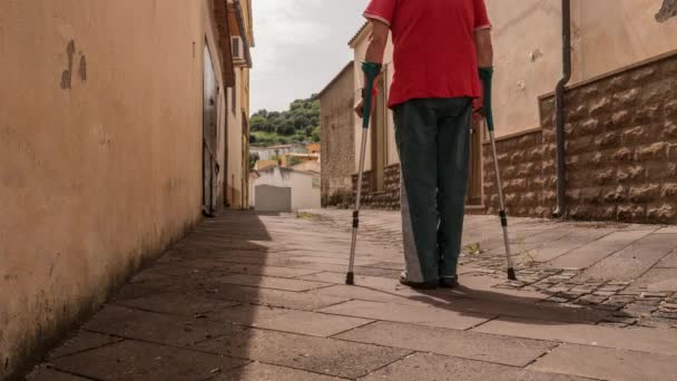 Upływ czasu stary starzec idący ulicą i alejki na kulach, robiący rehabilitację — Wideo stockowe