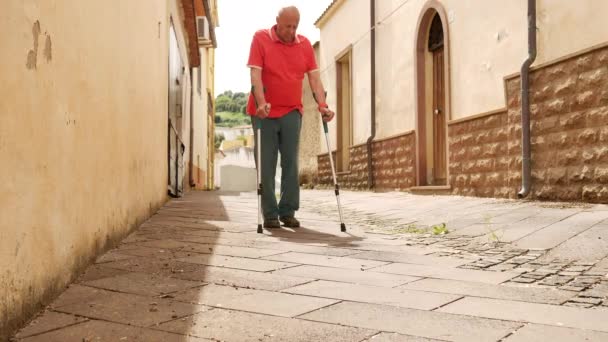 Egy boldog idős férfi sétál az utcán, mankókon sikátorozik, rehabilitációt végez, — Stock videók