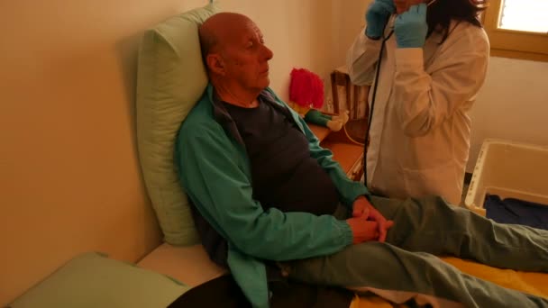 Domácí lékařské vyšetření s ženskou lékařkou, která navštíví staršího muže pacienta, zakrytí hrudníku, kontrola lymfatických uzlin. — Stock video