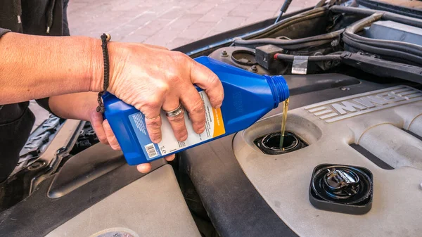Dodano olej silnikowy butelkowany bezpośrednio do komory silnika. mechanik dodając olej silnikowy na BMW 320 diesel. nowy olej. — Zdjęcie stockowe