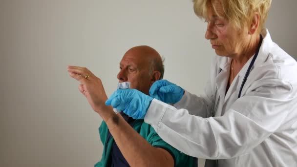 Posiniaczone ramię, a pacjentka asystuje lekarzowi. pomiar ciśnienia krwi i bandaż na ramię — Wideo stockowe