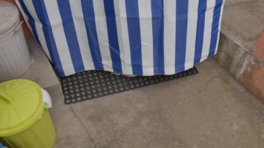 Bir guguk kuşu yapan paspasın kılları ve renkli perdeyle kapalı bir şekilde kapıdan çıkıyorlar. Ev temizliğinin güzel yorumu..