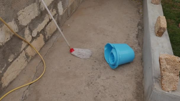 Mop z mopem pozostawione na ziemi, które są zalane, spryskane sprayem wody. — Wideo stockowe