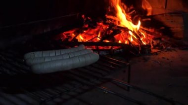 Beyaz Alman sosisi sosisi. Şöminede yemek pişirmek ya da ızgarada yemek pişirmek için çok güzel bir ateşin arka planına işlenmiş iki sosis..