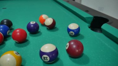 Renkli ve numaralandırılmış topları olan bilardo oyunu. Sekiz numara. Yeşil masa ve bilardo ıstakalı hareket eden toplar. Beyaz topu çeviriyor.. 