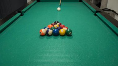 Renkli ve numaralandırılmış topları olan bilardo oyununu durdurun. Sekiz numara. Yeşil masa ve bilardo ıstakalı hareket eden toplar. Beyaz topu çeviriyor.